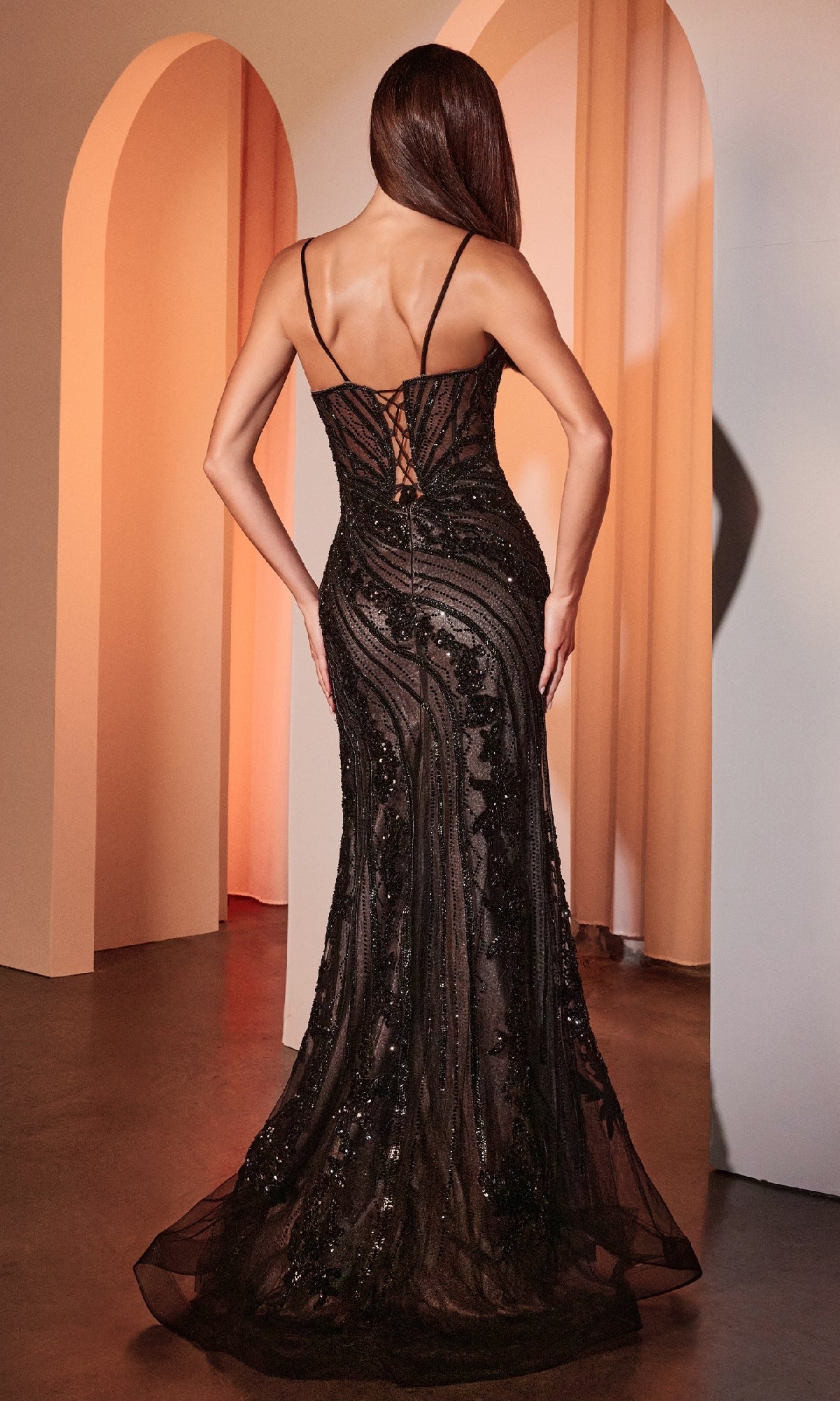 A woman faces away from the camera in the Long Beaded-Lace Prom Dress: Ladivine CC0389, featuring thin straps, intricate beaded lace, and a fit-and-flare silhouette, standing in a room with elegant arched doorways.